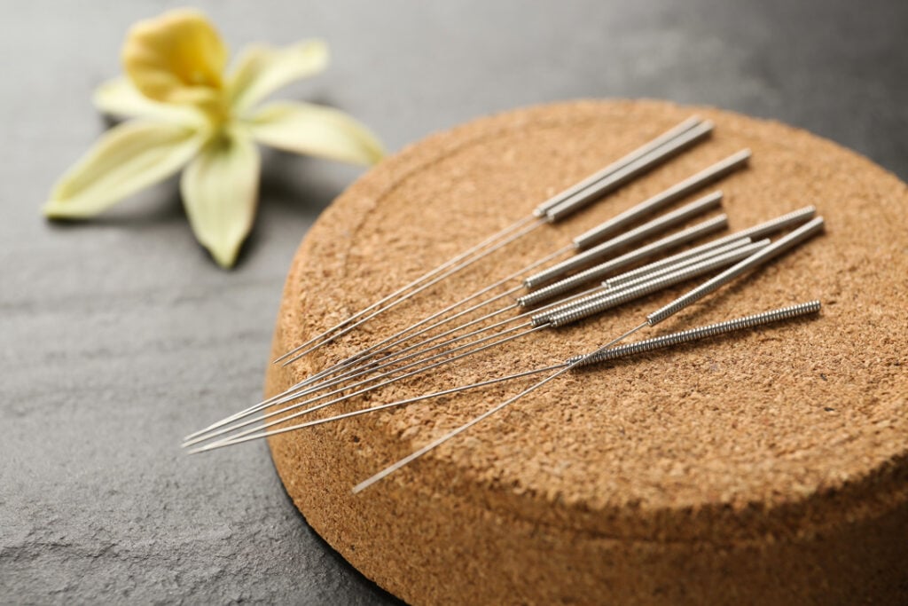 Cork coaster with acupuncture needles on black table