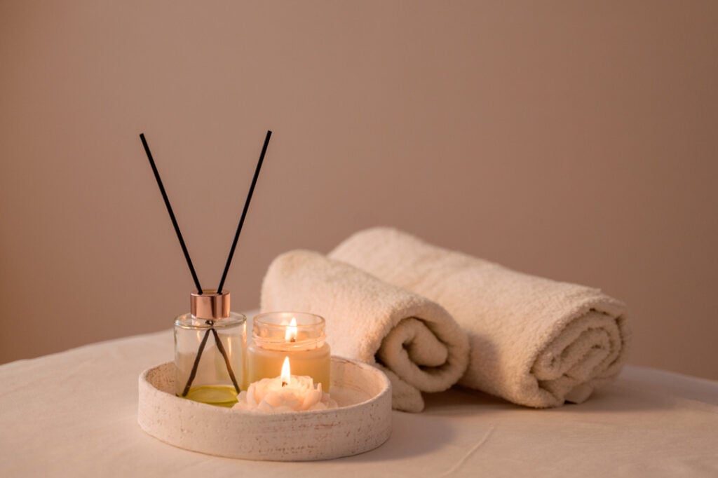 Lit candles and aroma sticks on a tray in a serene massage parlor, creating a relaxing and spa-like atmosphere